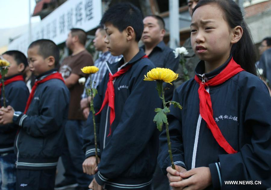 Le 12 mai 2013, dans le bourg de Yingxiu du district de Wenchuan dans le Sichuan, des enfants, une fleur à la main, ont rendu hommage aux victimes du séisme d'une magnitude de 8.0 qui a frappé la régions il y a cinq ans. (Photo : Xinhua/Bai Yu)