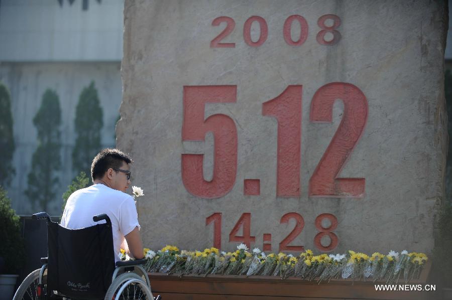 Un jeune homme en fauteuil roulant, qui a perdu ses jambes dans le séisme du Wenchuan il y a cinq ans, a tenu à rendre hommage aux victimes de la catastrophe devant un monument commémoratif à Beichuan dans la province du Sichuan, le 12 mai 2013. 