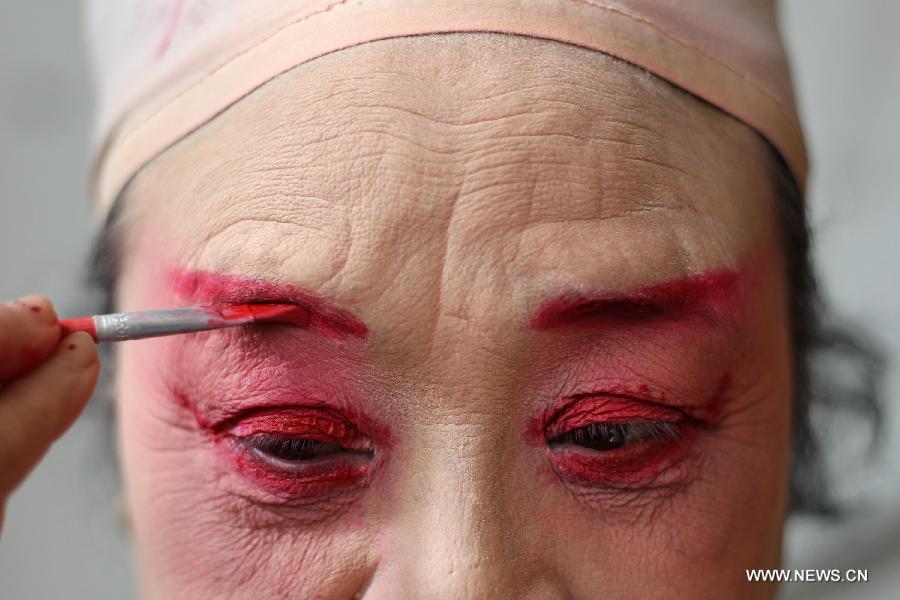 Image d'archive, prise le 31 janvier 2012 au Jardin des Chen dans la banlieue de Chengdu, capitale de la province du Sichuan, montrant une actrice du Troupe de l'opéra du Sichuan en pleine séquence de maquillage en coulisse. (Xinhua/Xue Yubin)