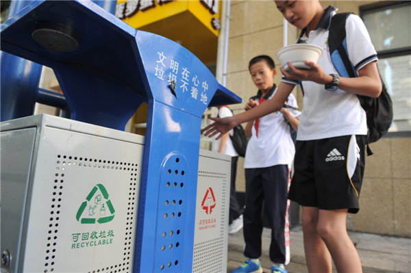 Les élèves jettent les déchets triés dans une poubelle, dans la ville de Lin'an, dans la Province du Zhejiang, le 17 juin 2013. La Journée Nationale du Bas Carbone a eu lieu cette année le 17 juin 2013, sur le thème ? Ayez une attitude pauvre en carbone et construisez de belles maisons ?. [Photo Hu Jianhuan / Asianewsphoto]