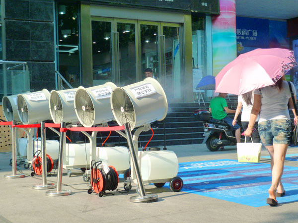 Cinq ventilateurs de refroidissement par pulvérisation sont opérationnels devant un magasin de Nanjing pour rafra?chir les clients et les passants, la province du Jiangsu dans l'est de la Chine, le 29 Juillet 2013.