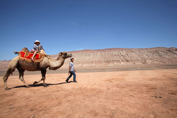 Un enfant sur le dos d'un chameau près des montagnes flamboyantes, un site touristique à Turpan, dans la région autonome ou?goure du Xinjiang, le 11 ao?t 2013.