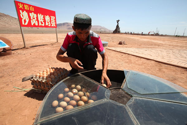 Un vendeur fait cuire des oeufs dans la rue où il y avait suffisamment de chaleur pour préparer ces oeufs comestibles près des montagnes flamboyantes, un site touristique à Turpan, la région autonome ou?goure du Xinjiang au nord de la Chine, le 11 ao?t 2013. Les oeufs, vendus à l'unité 5 yuans, sont devenus la grosse attraction parmi les touristes les plus curieux. Les monts Flamboyants doivent leur nom d'un roman classique chinois, Voyage à l'Ouest, qui raconte le pèlerinage de Xuan Zang, un moine bouddhiste, en Inde. La chaleur estivale fait de ces montagnes, l'un des endroits les plus chauds en Chine.