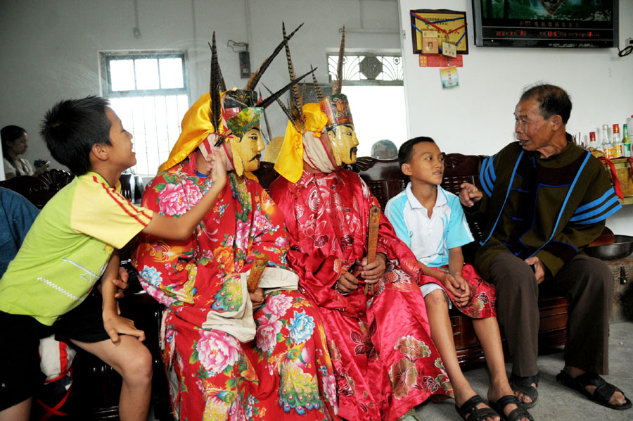 Le 18 ao?t 2013, dans le district autonome Maonan de Huanjiang dans la province du Guangxi, Tan Shengci et deux amis racontent des histoires à deux jeunes concernant leur culture, qui suivent chez l'atisan une formation pour apprendre la fabrication des masques de la danse Nuo. (Photo : Xinhua)