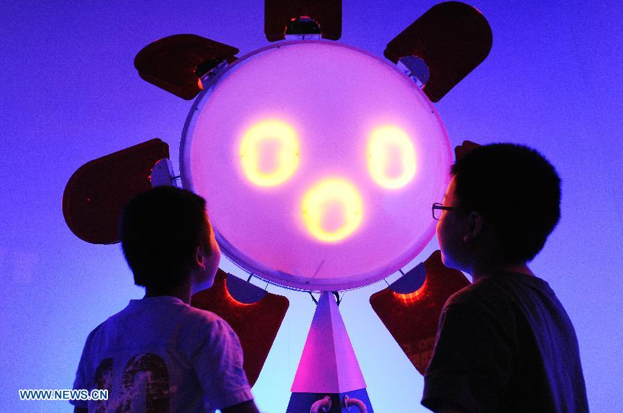 Deux enfants devant un dispositif pouvant prédire les jours ensoleillés et pluvieux au cours de l'édition 2013 de l'Exposition internationale ?Science et Art? de Shanghai, en Chine orientale, le 28 ao?t 2013. l'événement qui va durer six jours a débuté mercredi au Shanghai Exhibition Center.