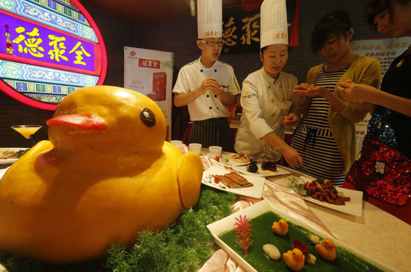 Une patisserie en forme de canard, présentée chez Quanjude, un restaurant chinois de Beijing célèbre pour son canard laqué, le 1er septembre 2013. Ces petites gourmandises en forme de canard seront vendues pour 22 Yuans (3,60 Dollars US) la demi-douzaine. Ces canards sont confectionnés à base de citrouille et de riz gluant. Beijing va devenir la deuxième ville de Chine après Hong Kong à exposer le fameux ? canard en caoutchouc ? de 18 mètres de haut, con?u par l'artiste néerlandais conceptuel Florentijn Hofman, entre le début de septembre et la fin d'octobre. [Photo / Asianewsphoto]