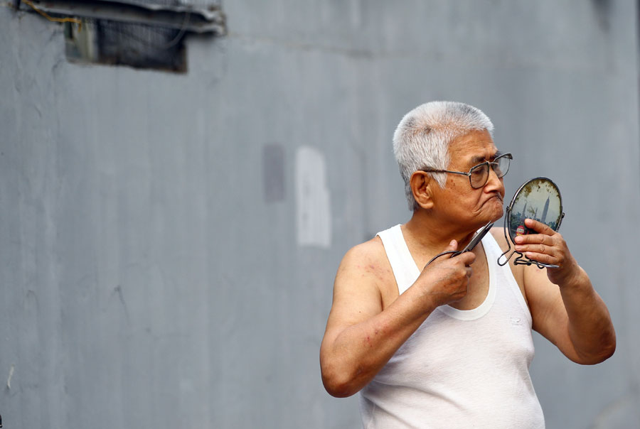 Un vieil homme se rase dans un hutong de Beijing. [Photo Zou Hong / China Daily]