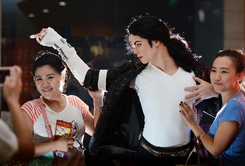 Deux admiratrices aux c?tés de la statue de cire à l'effigie du regretté roi de la pop Michael Jackson, destinée à la future branche du musée de cire de Madame Tussauds à Wuhan, la province du Hubei, le 15 septembre 2013 (ce modèle ayant été exposé dans un centre commercial). [Photo: Zhou Chao/Asianewsphoto]