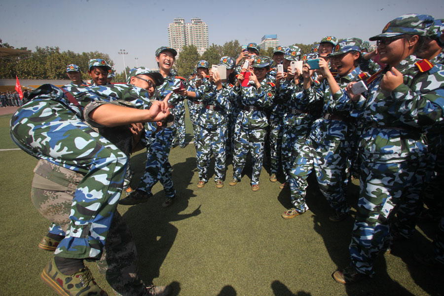 Les élèves et leur instructeur posent pour des photos après la formation militaire des nouveaux étudiants à l'Université du Shandong, à Jinan, dans la Province du Shandong en Chine de l'Est, le 26 septembre 2013. [Photo Zheng Tao / Asianewsphoto]