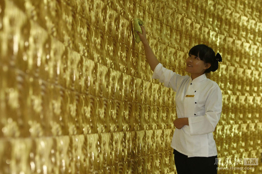 Au village de Huaxi, un membre du personnel époussète les murs décorés d'or du ? Golden Club ? du Huaxi Longxi International H?tel. C'est le plus luxueux des clubs à thème, puisqu'il comporte 5 éléments : l'or, le bois, l'eau, le feu et la terre.