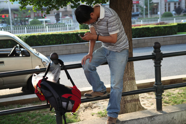 Un homme occupé à consulter son mobile dans une rue de Beijing, le 1er septembre 2013.