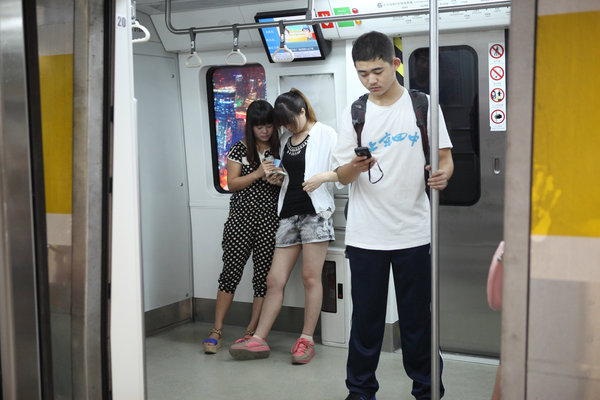 Des usagers avec leurs mobiles dans le métro à Beijing, le 30 ao?t 2013.