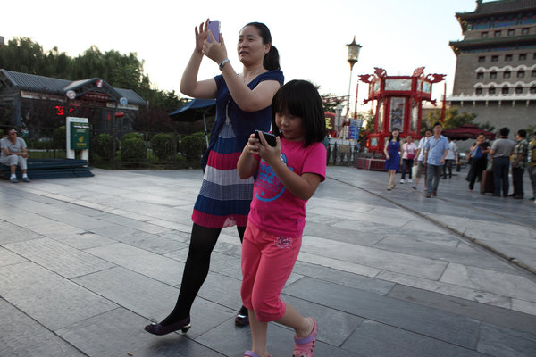 Une mère et sa fille, toutes les deux avec leurs téléphones, tout en marchant dans une rue de Beijing, le 31 ao?t 2013.