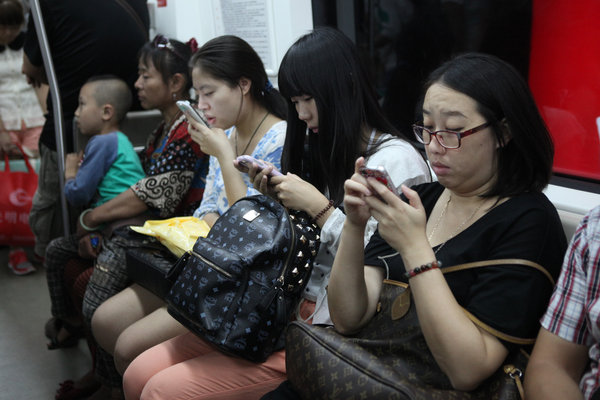 Des personnes regardant leurs mobiles dans le métro de Beijing, le 30 ao?t 2013.