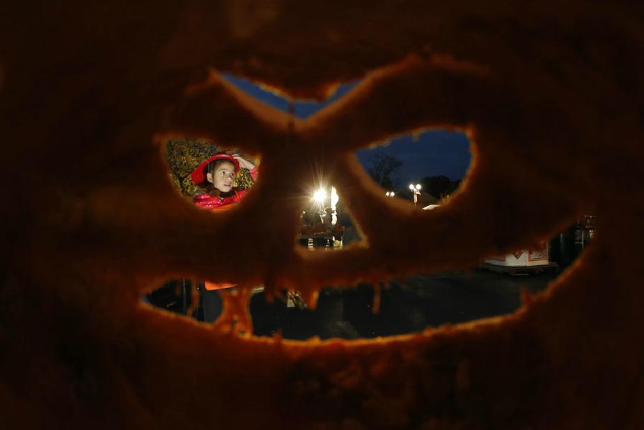 Une jeune fille est aper?ue à travers l'une des milliers de citrouilles sculptées à l'occasion du Grand Festival américain de la citrouille à Highwood, dans l'Illinois, le 18 octobre 2013. 