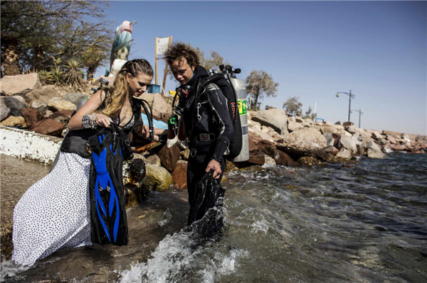 Un mannequin (à gauche) entre dans l'eau avant une séance de photos sous-marines en Mer Rouge, au large de la ville balnéaire d'Eilat, le 23 octobre 2013. [Photo / agences]