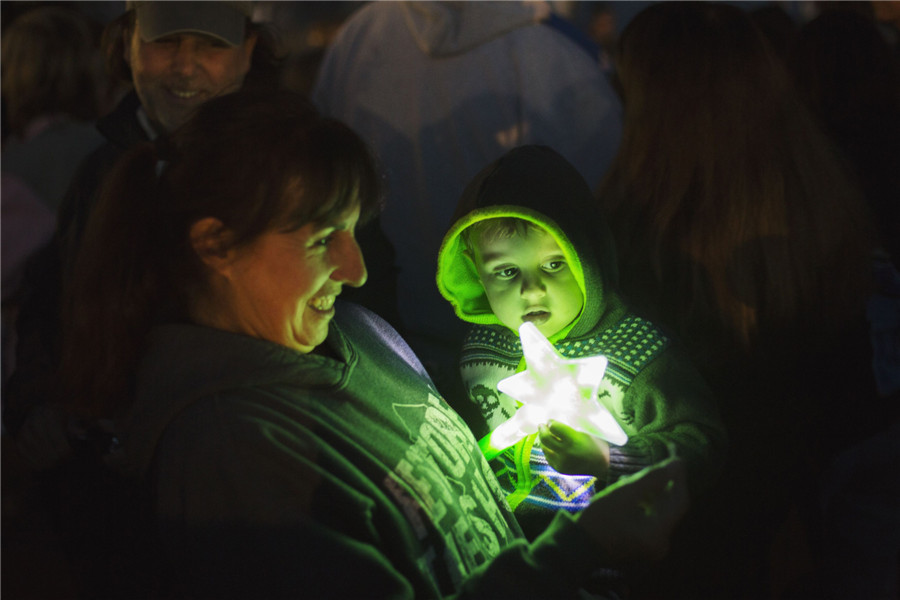 Une femme et son enfant tenant un jouet participent à une manifestation d'illumination de la c?te pour le premier anniversaire de l'ouragan Sandy à Seaside Heights, dans le New Jersey, le 29 octobre 2013.