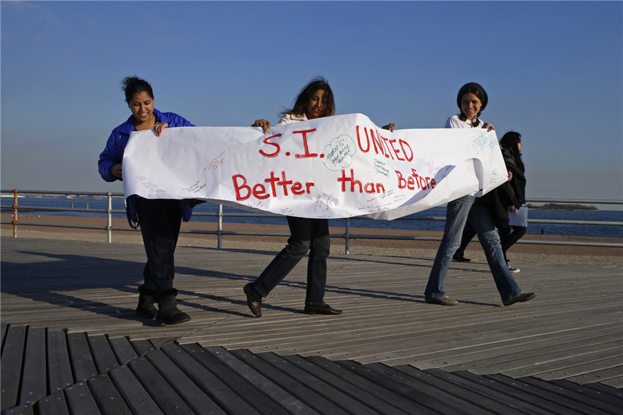 Des habitantes de Staten Island montrent un calicot alors qu'elles marchent lors d'une manifestation organisée sur la promenade de la rive sud pour commémorer le premier anniversaire de l'ouragan Sandy dans l'arrondissement de Staten Island de la ville de New York, le 29 octobre 2013.