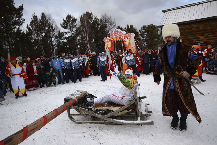 Le relayeur de la flamme olympique des Jeux d'hiver de Sotchi, Alexander Chudnovskiy, monte sur un tra?neau du musée Taltsy dans la région d'Irkoutsk, document du Comité d'organisation de Sotchi 2014 publié le 23 novembre 2013.