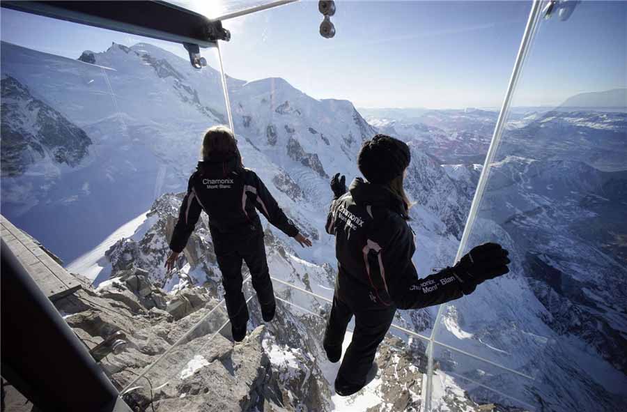 Des employés, portant des pantoufles pour protéger le plancher de verre, marchent sur l'installation ??Un pas dans le vide?? lors d'une visite de presse au sommet de la montagne de l'Aiguille du Midi à Chamonix, dans les Alpes fran?aises, le 17 décembre 2013. [Photo / agences]