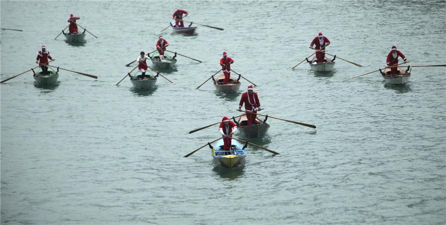 Des gens vêtus de costumes de Père No?l font du bateau sur le Grand Canal de Venise, le 21 décembre 2013. [Photo / agences]