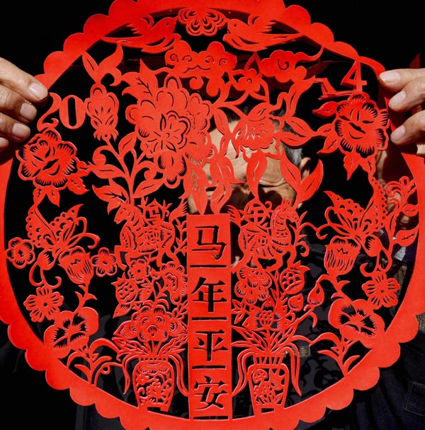 Chen Longyong montre son travail de découpage de papier, le 29 décembre 2013. L'artiste né dans les années 70 est natif de Yancheng, la province du Jiangsu, passionné par cet art depuis plus de 40 ans. Récemment, il a créé plusieurs ?uvres sur le thème des chevaux, pour accueillir la nouvelle année, soit l'année du cheval selon le calendrier du zodiaque chinois. [Photo/Xinhua]