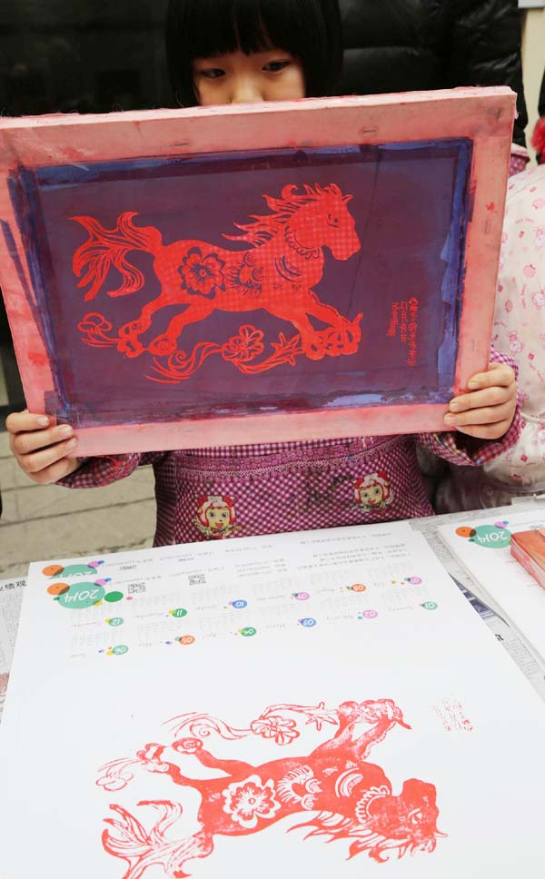 Une jeune fille de Xiangyang, dans la province du Hubei, fait des copies d'une peinture du Nouvel An sur le thème du cheval en utilisant la technique de la sérigraphie.