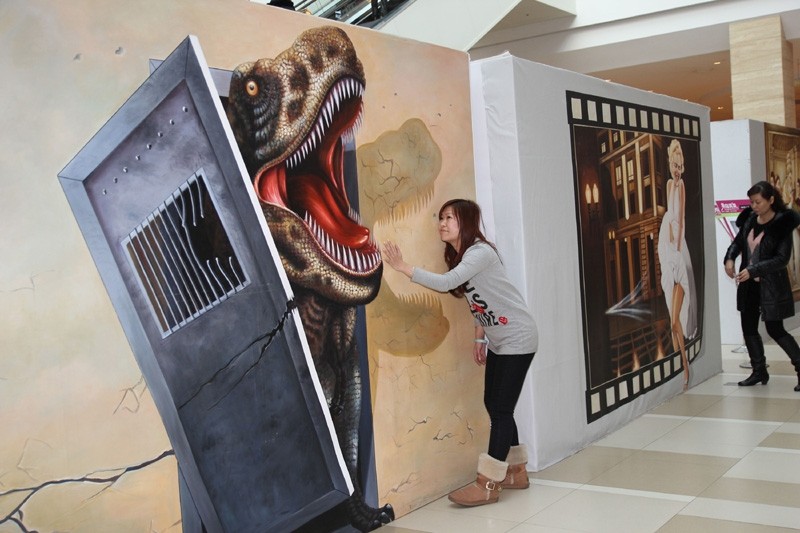 Une visiteuse pose pour une photo devant une peinture 3D dans un centre commercial de Qingdao, dans la Province du Shandong, dans l'Est de la Chine, le 11 février 2014. L'exposition de peintures 3D a été ouverte gratuitement aux visiteurs pour accueillir la prochaine Fête des Lanternes, qui a lieu le quinzième jour du premier mois lunaire. [Photo Huang Jiexian / asianewsphoto]