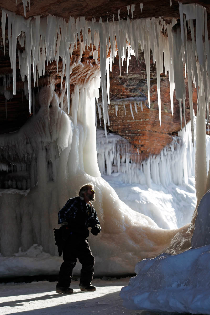 Terry Komarek, de Wausau, dans le Wisconsin, regarde des gla?ons sur le pont d'une formation rocheuse près des grottes sous-marines de l'Apostle Islands National Lakeshore du Lac Supérieur, près de Cornucopia, dans le Wisconsin, le 14 février 2014. [Photo/agences]