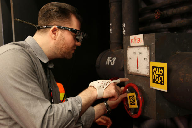 Un journaliste essaye un prototype de Fujitsu, un gant intelligent aux spécifications AR. [Photo/CNET]