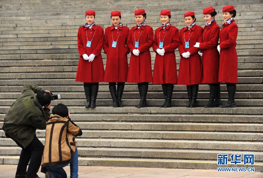 Lundi 3 mars, deux journalistes photographient des h?tesses d'accueil de la 2ème session du 12e Comité National de la CCPPC devant le Palais du Peuple à Beijing. (Xinhua/Di Zihe)