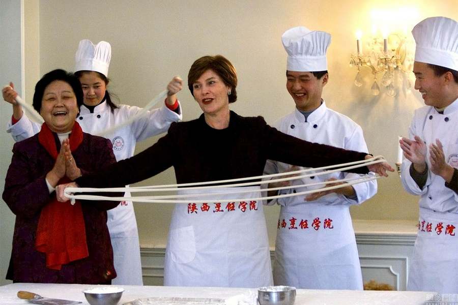 Le 21 févier 2002 à Beijing, Laura Bush apprend à faire les ? nouilles tirées ? auprès d'un chef chinois dans l'ambassade américaine. 