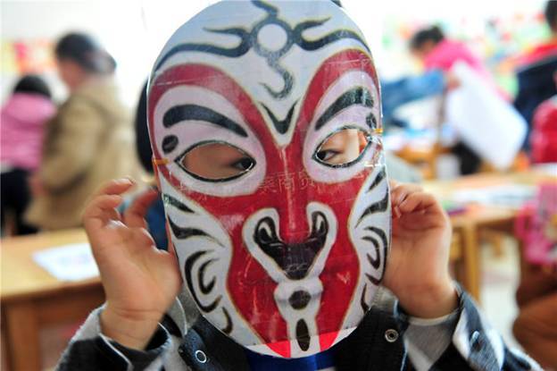 Un enfant montre son masque d'opéra fait à la main dans une école maternelle du Comté de Zigui, dans la Province du Hubei, le 26 mars 2014, pour célébrer la Journée mondiale du théatre.