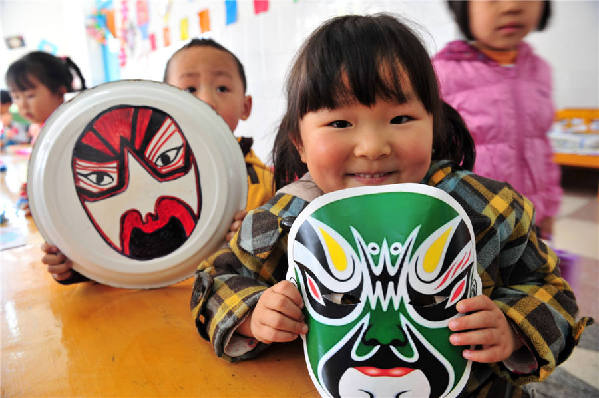 Des enfants montrent leurs masques d'opéra faits à la main dans une école maternelle du Comté de Zigui, dans la Province du Hubei, le 26 mars 2014, pour célébrer la Journée mondiale du théatre.