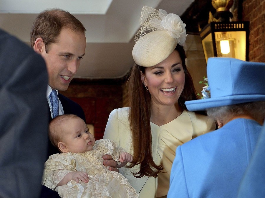 Le Prince William porte son fils, le Prince George, alors qu'il arrive avec sa femme Kate, Duchesse de Cambridge pour le baptême de leur fils au palais St James à Londres, le 23 octobre 2013.