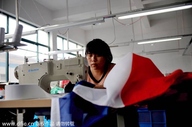 Une ouvrière d'usine coud un drapeau national dans les locaux de la société Hanghzou Donghao Flag Co, dans la province du Zhejiang, en Chine de l'Est, le 8 avril 2014. Le fabricant, qui compte moins de 20 employés, a commencé à recevoir une rafale de commandes pour la Coupe du monde l'an dernier et a produit environ 400 000 drapeaux. Le dernier lot devra être livré au plus tard le 14 avril, deux mois avant la cérémonie d'ouverture. La Province du Zhejiang est depuis longtemps l'un des p?les manufacturiers de la Chine.