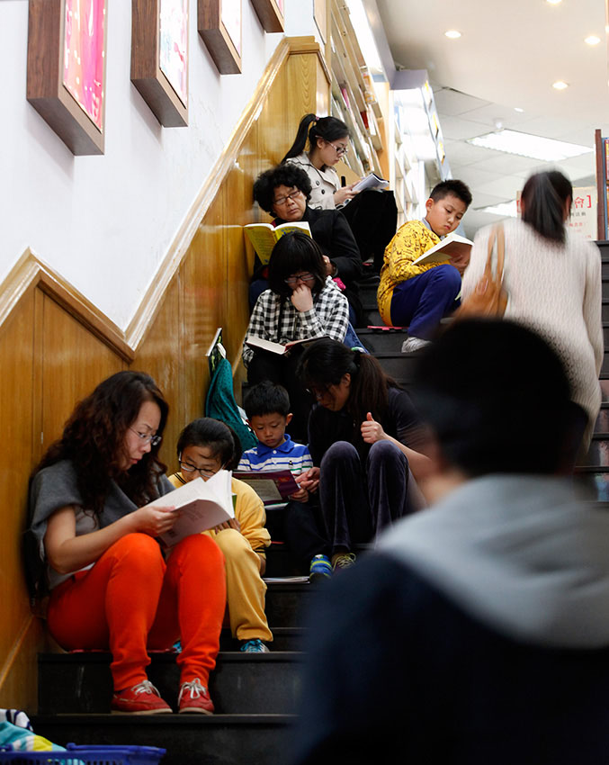 Le 18 mai 2014, dans la librairie Sanlian Taofen à Beijing, des gens occupés à lire sur les marches de l'escalier menant au sous-sol de la boutique. (Photo : Xinhua/Shen Bohan)