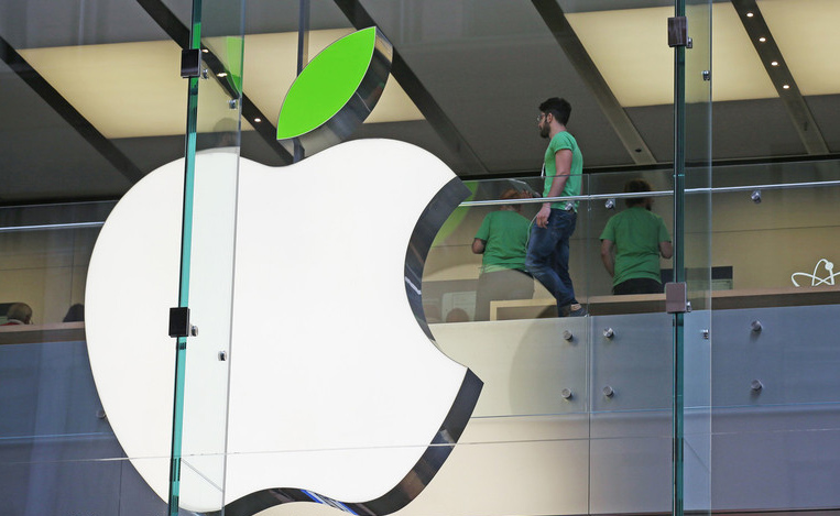 Les employés portent des chemises vertes, près du logo familier d'Apple -avec cependant une feuille verte- affiché sur la boutique pour marquer la célébration annuelle de la Journée de la Terre à Sydney, le mardi 22 avril 2014. Apple offre gratuitement le recyclage de ses produits utilisés et promet de l'appliquer dans l'ensemble de ses boutiques, bureaux et centres de données avec de l'énergie renouvelable pour réduire la pollution causée par ses dispositifs et services en ligne .