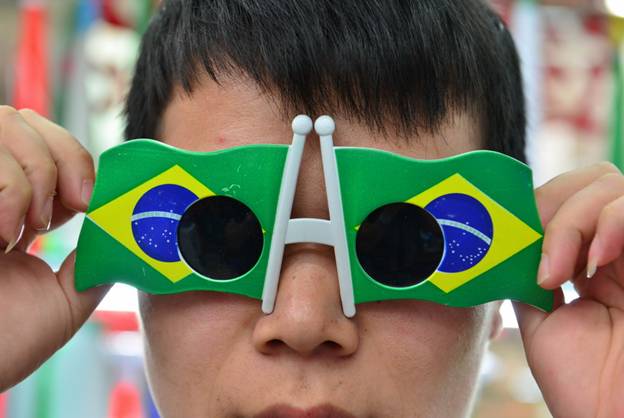 Un jeune gar?on essaie sur des lunettes de soleil sur le thème de la prochaine Coupe du Monde au Brésil à la Cité du Commerce International d'Yiwu.