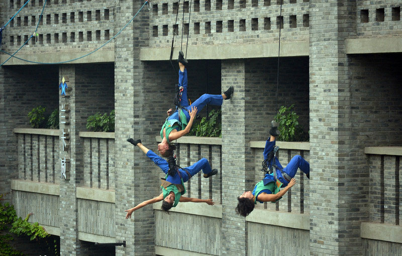 Reliés par un cable, trois danseurs professionnels ont offert au passants une performance spectaculaire sur le mur extérieur d'un batiment de la ville de Chongqing du sud-ouest de la Chine, le 9 mai 2014. Dans cet art, les danseurs ont créé l'illusion de voler et de défier la gravité. 